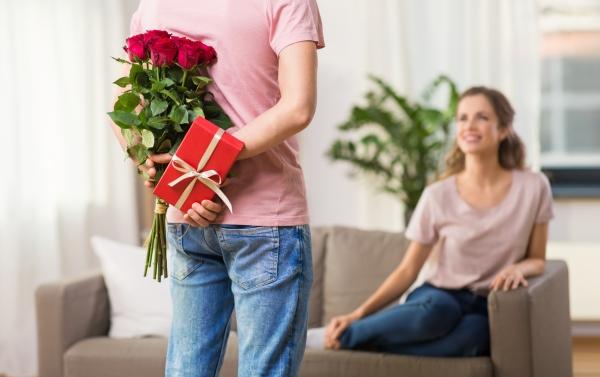 Mann versteckt Blumen und Geschenk hinter seinem Rücken Mann versteckt Blumen und Geschenk hinter seinem Ruecken