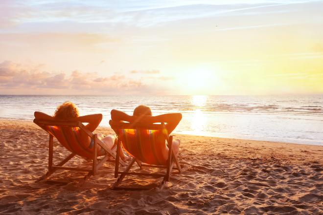 Gemütliche Liegen sind perfekt am Strand, bieten aber auch zuhause Entspannung pur Paar liegt am Strand in Liegestühlen - Gemütliche Terrassenliegen als Alternative für zuhause