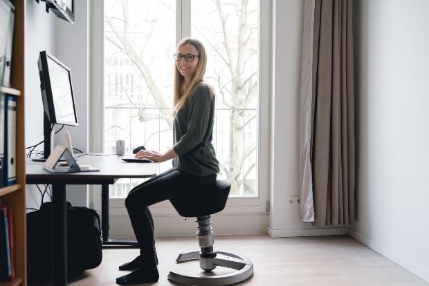 Eine ergonomische Sitzposition ist wichtig für die Rückengesundheit Frau sitzt aufrecht auf ergomischem Hocker - Ergonomie am Arbeitsplatz