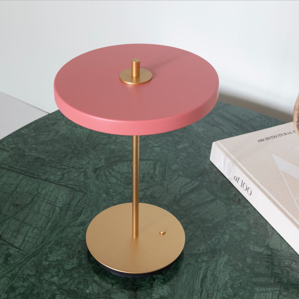 Pinker Lampenschirm, goldener Standfuß. Die neue Asteria Move Tischleuchte kann auch knallig.
