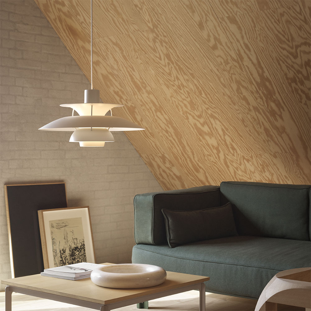 Hygge – so wird Wohnen zum Wohlfühlen 6 Hygge-Momente kreiert die PH5 auch im Wohnzimmer. In Weiß harmoniert die Poulsen Leuchte perfekt mit dem dunkelgrünen Sofa und der Dachsräge aus hellem Holz.